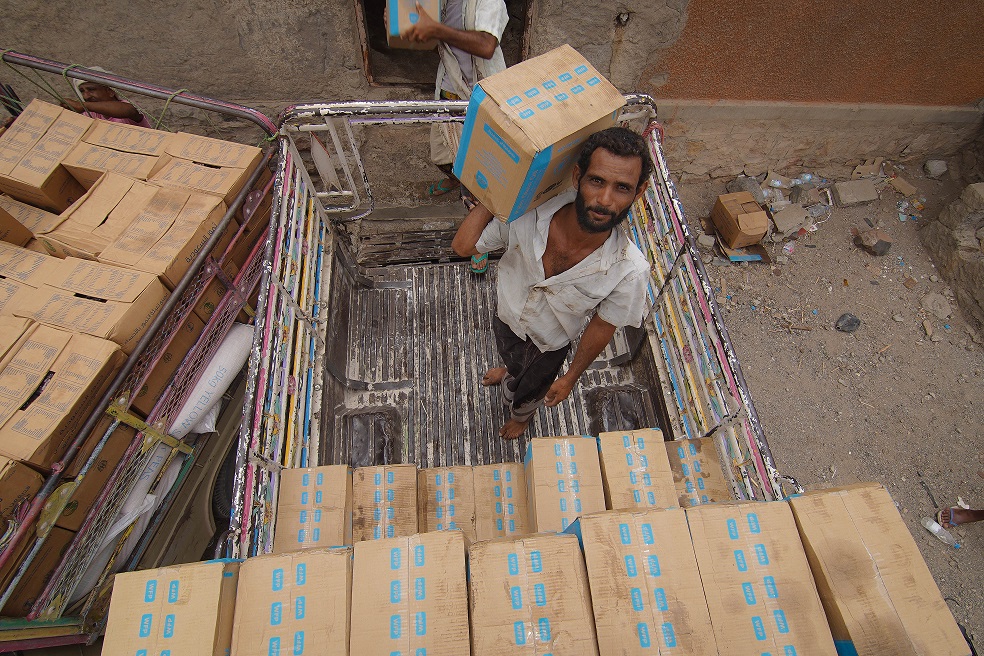 Jemeniläismies WFP:n ruoka-avustuslaatikon kanssa. 