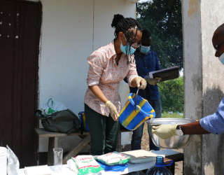 Elintarvike- ja markkinaosaston vanhempi tutkija Louise Abayomi (Postharvest-hankkeesta), valmistelee fufua näytteenottoa varten ja näyttää kongolaiselle ryhmälle, miten jauhoja, vettä ja ravinteita annostellaan oikea määrä. Kuva: WFP/Alice Rahmoun