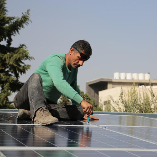 Mies asentaa aurinkopaneelia katolla