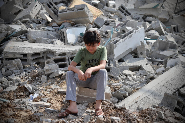 Poika raketin osuman kohteeksi joutuneen rakennuksen raunioiden vieressä Gazan kaupungissa.