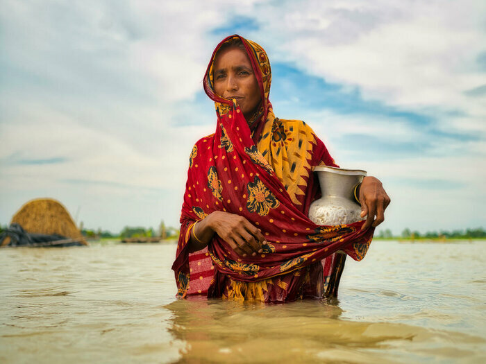 Nainen kantaa ruukkua veden ympäröimänä
