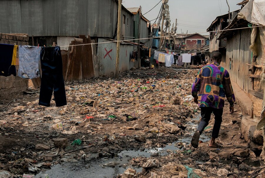 A man walks through sewage and garbage on a street in the Mukuru Kwa Reuben informal urban settlement in Nairobi. Photo: WFP/Alessandro Abbonizio