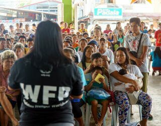 WFP:n henkilökunta selittää rekisteröintiprosessia Irosinin yhteisön jäsenille, jotka osallistuvat ennustepohjaiseen rahoitushankkeeseen. Kuva: WFP Philippines/Arete