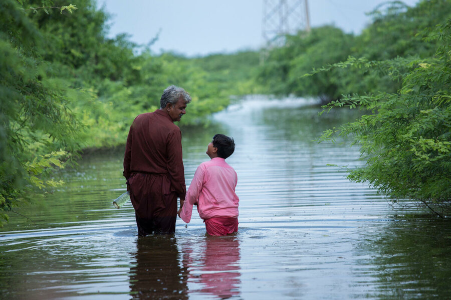 Pakistan: Abdul Jabbar and his son Muhammad Hashim walk through flood water after their home was devastated by a monsoon. Photo: WFP/Saiyna Bashir